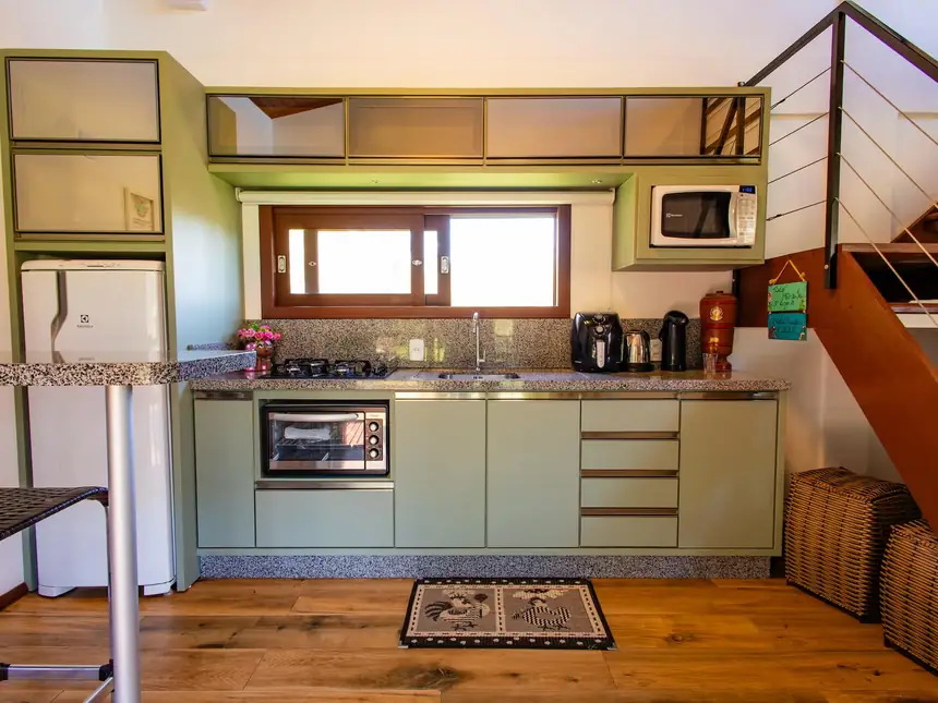 Cozinha compacta em tons de verde, com escada ao lado