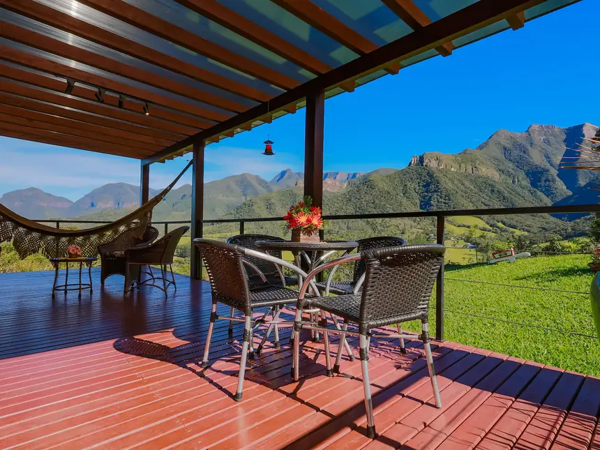 Deck de madeira com rede e mesa, de frente para o vale