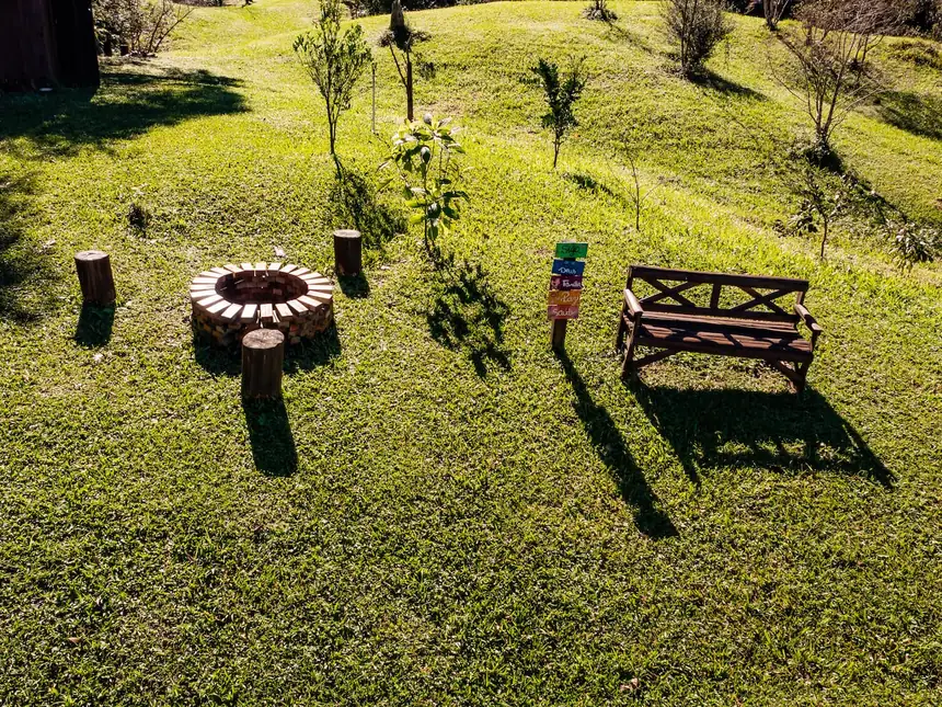 Área de fogueira no gramado, com bancos de madeira