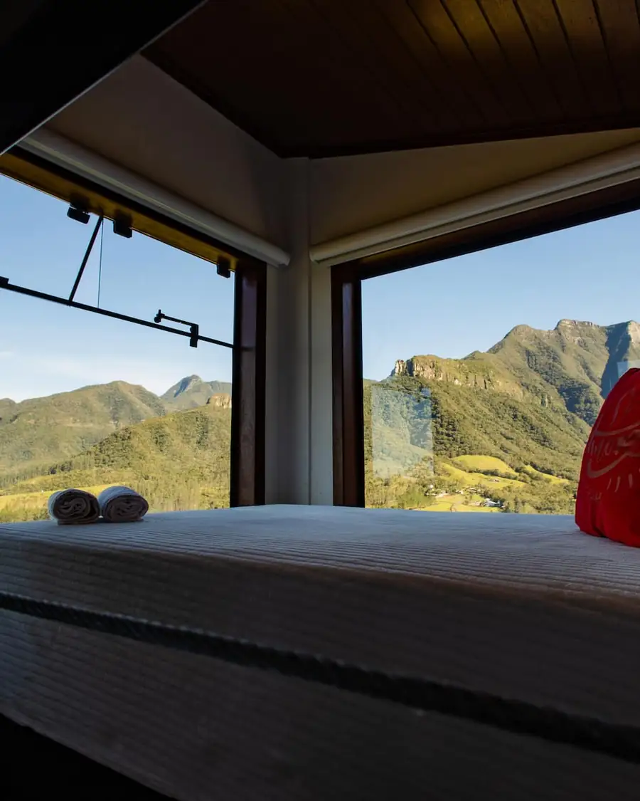 Cama de casal diante da janela com vista para as montanhas