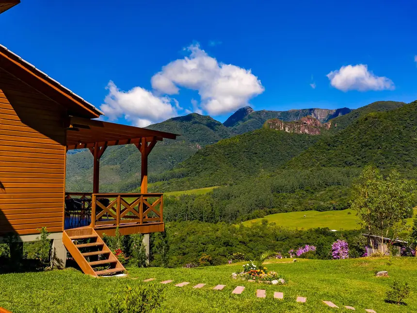Quintal gramado ao redor do chalé, com as montanhas