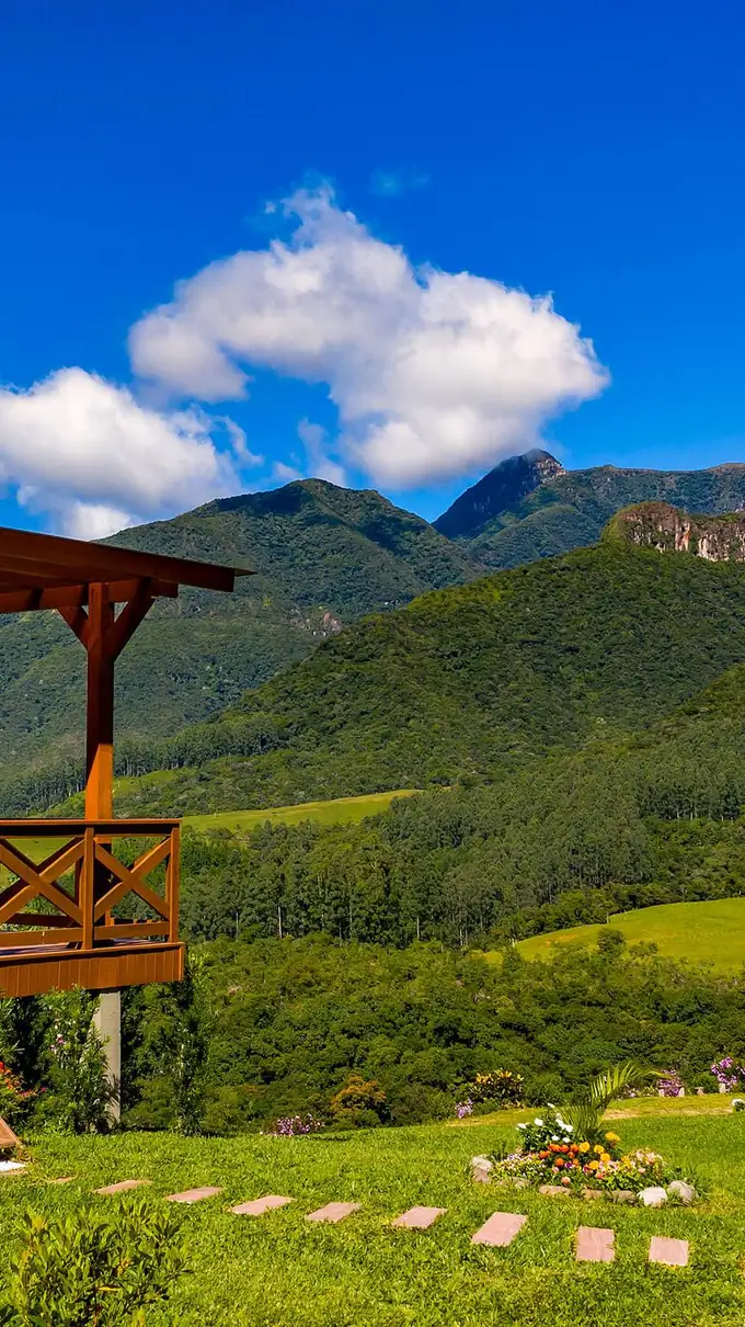 Lateral do chalé com o gramado e as montanhas